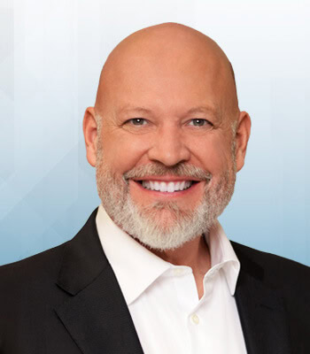 A headshot-style photo of a man smiling towards you