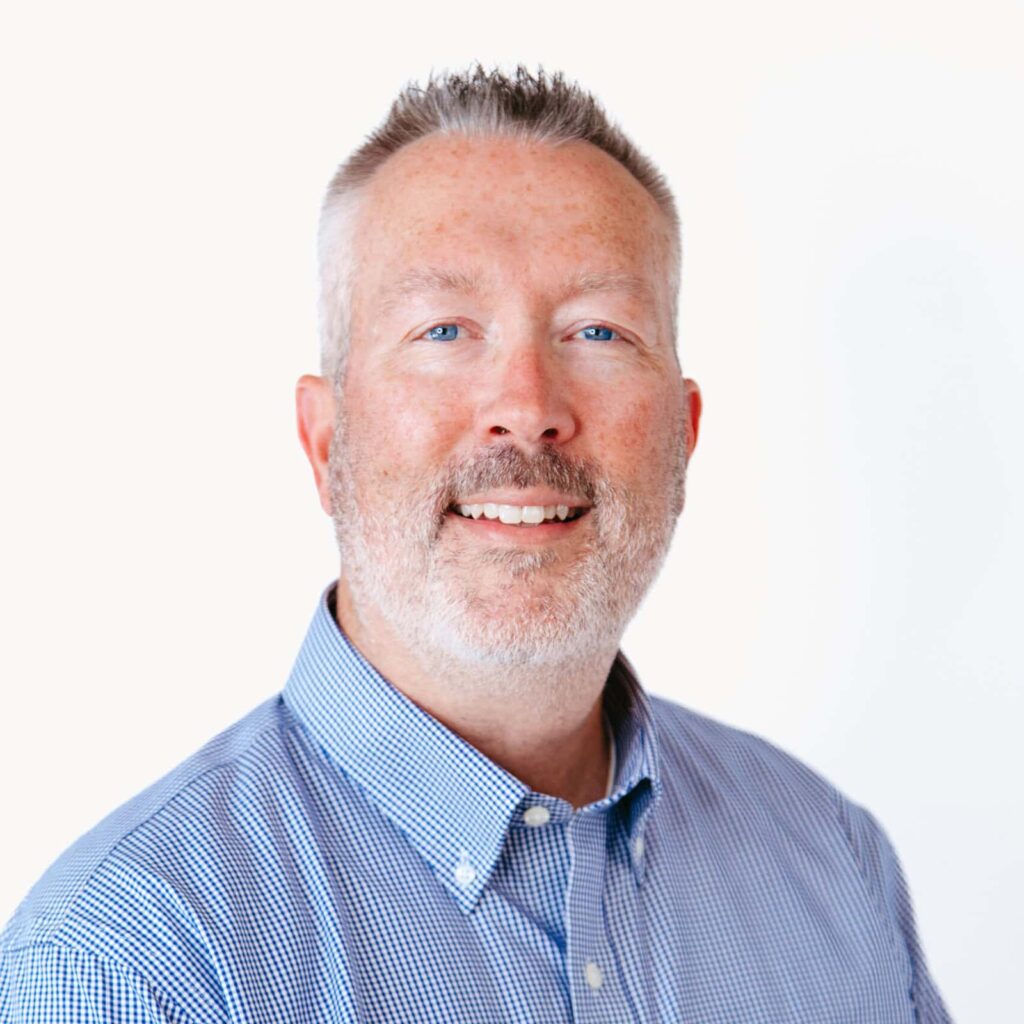 A headshot photo of a man smiling at you.
