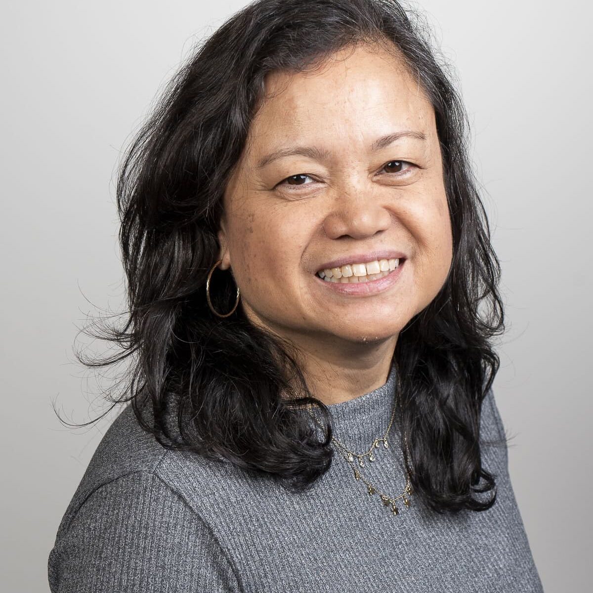 A woman with long black hair smiling.
